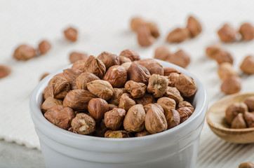 Hazelnuts in a bowl, spoon on the towel