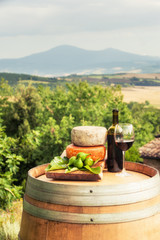 Red wine, cheese, figs on a wooden barrel in the background of t