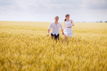 series. a love story. couple runs in the wheat field and smiling