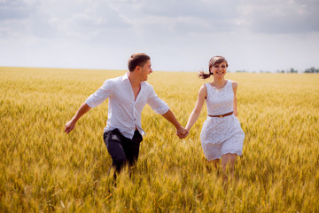 Fototapeta na wymiar series. a love story. couple runs in the wheat field and smiling