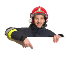 Smiling fireman in red helmet pointing at the blank banner