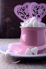 Pink ceramic mug on the wooden background full of sweet hearts