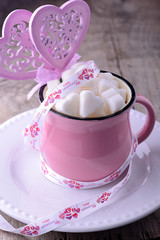 Pink ceramic mug on the wooden background full of sweet hearts