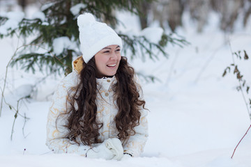 young girl lying  in the snow and laugh in winter forest