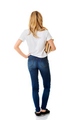 Fototapeta premium Back view of young woman holding books