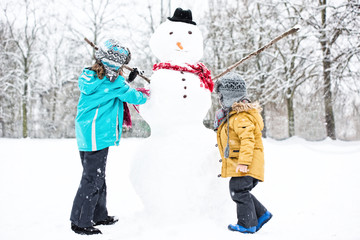 Kinder bauen Schneemann im Winter