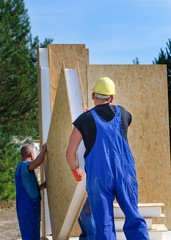 Two builders installing a wooden wall panel