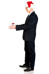 Mature businessman wearing santa hat holding gift