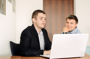 Young Businessmen Looking at Laptop on Table