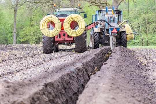 Two Agriculture Tractors Digging Drainage Pipes In Ground