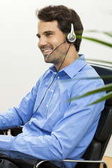 Attractive unshaven young man wearing a headset offering online 