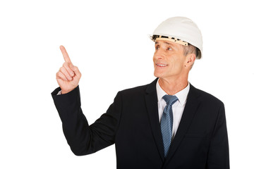 Smiling businessman with hard hat pointing up