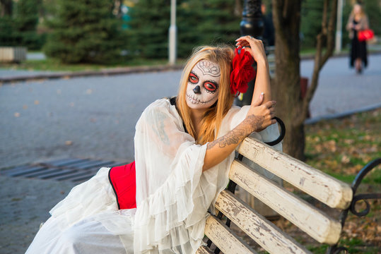 The girl in the image of Santa Muerte is sitting on a bench