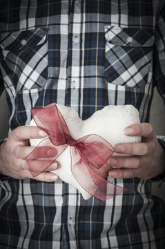 Man in plaid shirt holding a fabric heart with a red ribbon