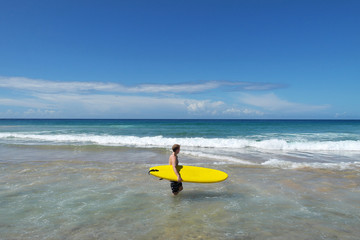 Surfer mit Surfboard alleine am Strand