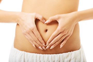 Close up female making heart shape on belly