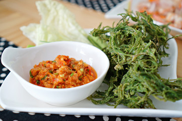 Thai chilli spicy sauce with fried and fresh vegetables on white