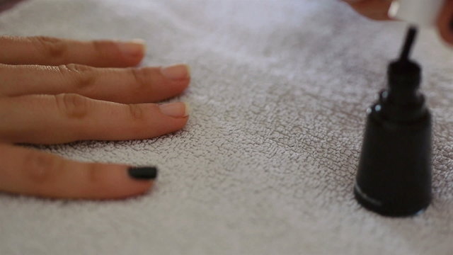 Woman nails polish on white towel close up
