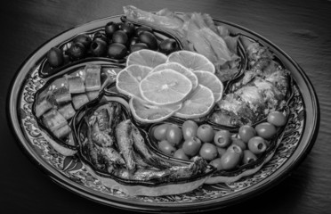 Assorty of fish, olives, lemon slices on oriental dish. Toned