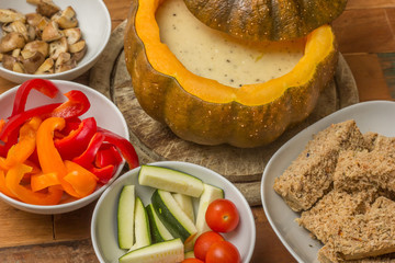 Cheese fondue in a roasted pumpkin with bread and vegetables © venemama
