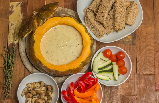 Cheese fondue in a roasted pumpkin with bread and vegetables