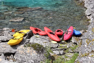 Selbstklebende Fototapeten Seven kayaks on the river bank. © makarova