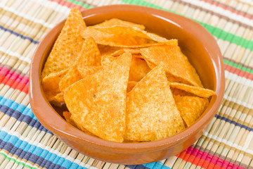 Totopos - Mexican tortilla chips on a colourful background.