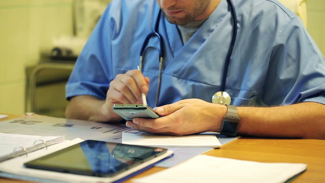 Young male doctor using modern smartphone in the hospital