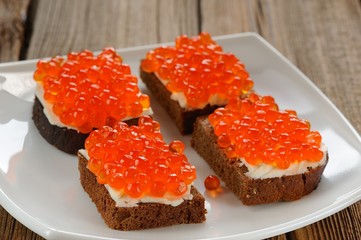 Red caviar on rye bread and butter on white plate
