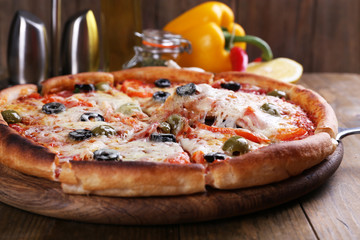 Pizza with cheese on board and wooden table background