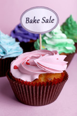 Delicious cupcakes with inscription on color background