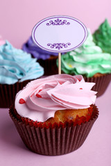 Delicious cupcakes with inscription on color background
