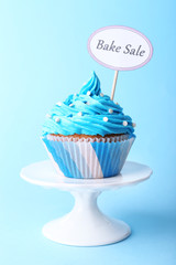 Delicious cupcake with inscription on blue background