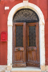 A weathered wooden door in an old red building - background