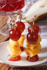 Red grapes and cheese on skewers close-up vertical
