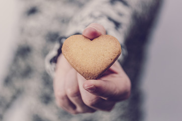 Obraz premium Woman holding a heart shaped butter biscuit. Valentine's day