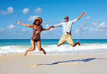 Happy couple jumping on the beach.