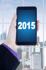 Manager hands holding smartphone with number 2015