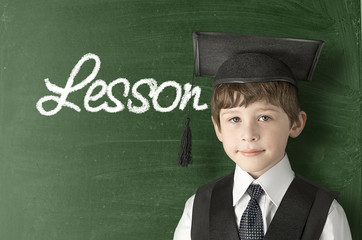 Cheerful little boy on blackboard. Looking at camera