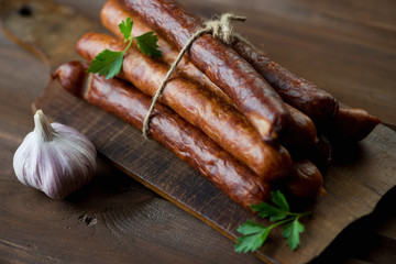 Rustic chopping board with smoked sausages, studio shot