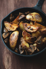 Roasted unpeeled potato slices with mushrooms, close-up