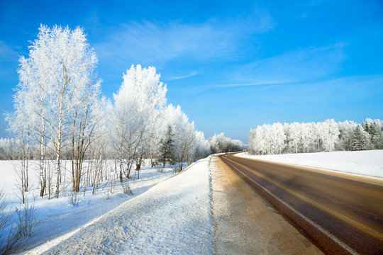 winter landscape with the road the forest and the blue sky