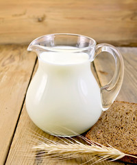 Milk in glass jug with bread on board