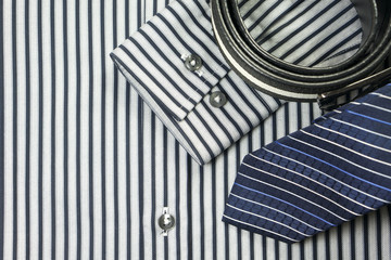 Fototapeta na wymiar Tie and belt on striped shirt background