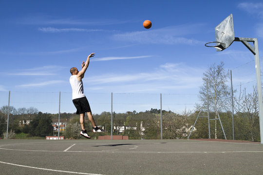 Basketball player taking a jump shot on an outdoor court