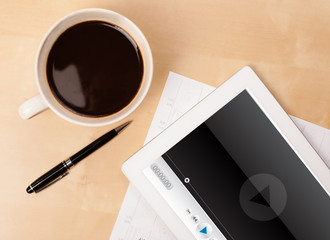 Tablet pc showing media player on screen with a cup of coffee on