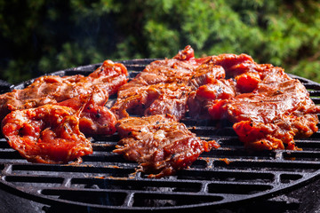 Grilling pork steaks on barbecue grill