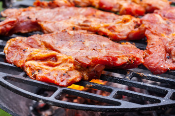 Grilling pork steaks on barbecue grill