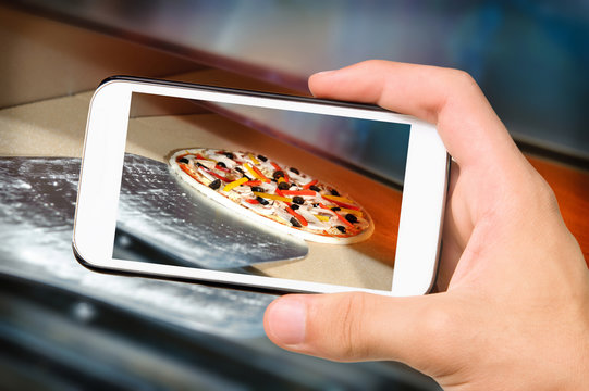 Hands taking photo pizza with smartphone