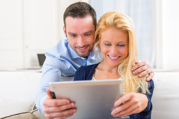 Young attractive couple having fun using tablet